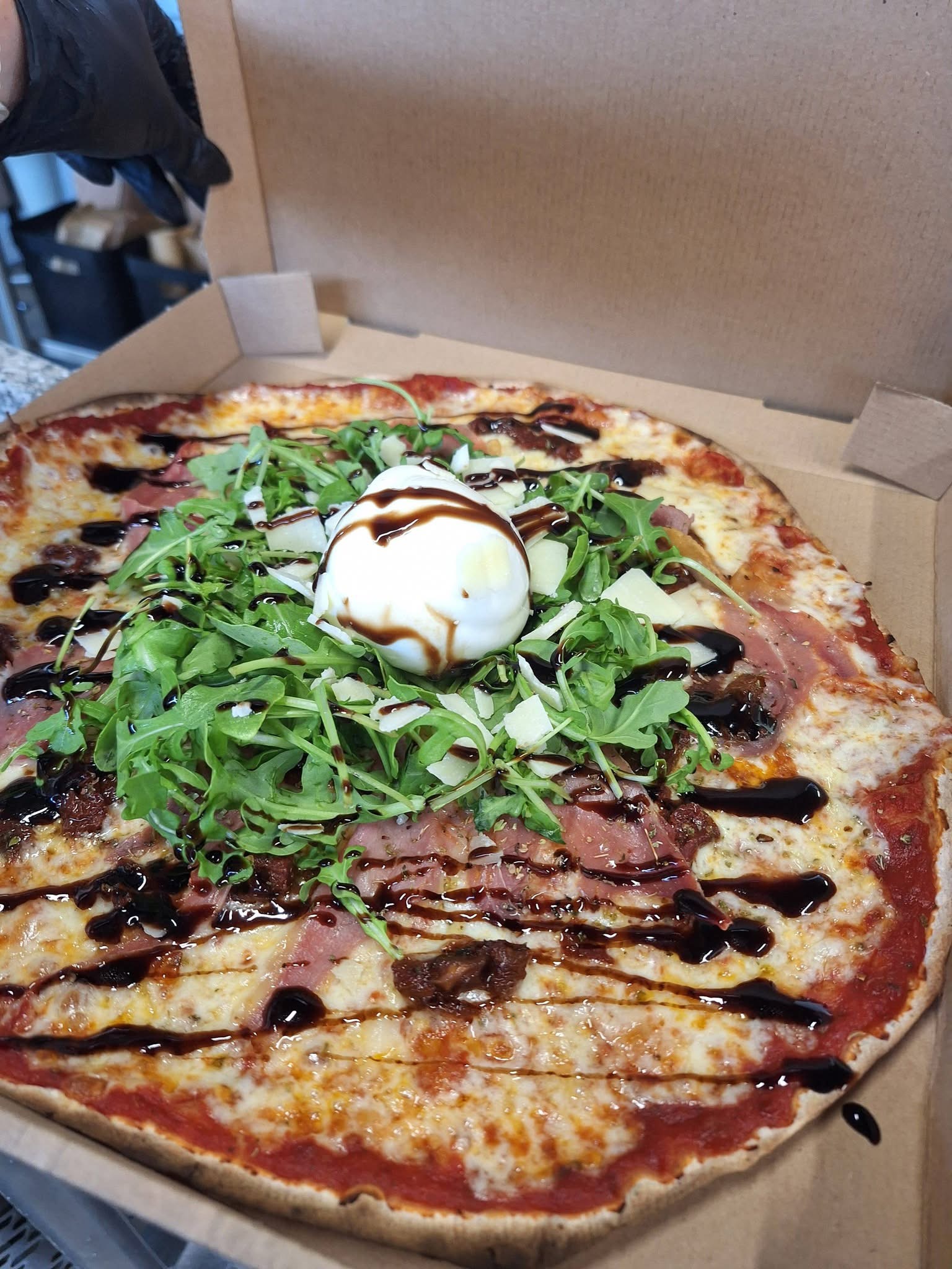 Pizza Burrata garnie de roquette, burrata et crème balsamique dans sa boîte